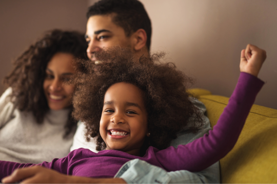 a couple with their daughter smiling on the sofa a couple with their daughter smiling on the sofa