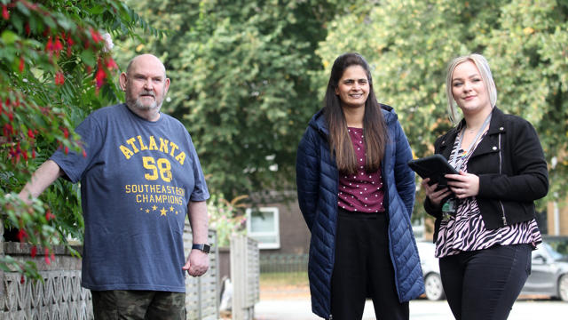 Two Irwell Valley Employees walking with a resident on the path