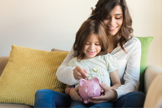 A woman with her child putting coins in the piggybank A woman with her child putting coins in the piggybank